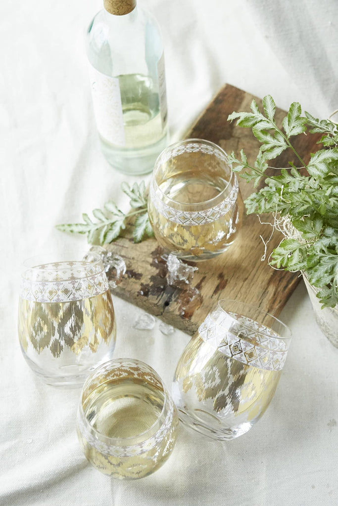 Patina Vie White Twist Stemless Wine Glass on table with wood board and wine botltle